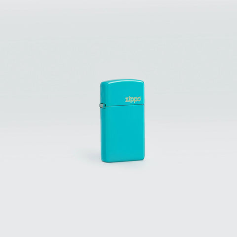 Lifestyle image of Zippo Slim Flat Turquoise Zippo Logo Pocket Lighter standing in a grey scene.