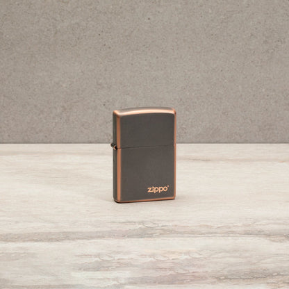 Lifestyle image of Classic Rustic Bronze Zippo Logo Windproof Lighter standing on a countertop.