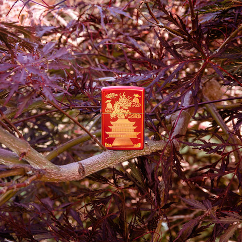 Lifestyle image of Eastern Design Dragon Design Metallic Red Windproof Lighter standing in a tree.