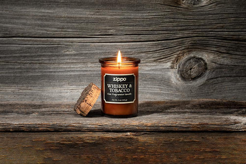 Lifestyle image of Front of Spirit Candle - Whiskey & Tobacco lit on a wooden stand with a wooden background