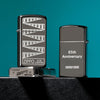 Lifestyle image of three Slim® Black Ice® 65th Anniversary Collectible Windproof Lighters. The lighter showing the front of the design, one showing the back, and one showing the unique bottom stamp.